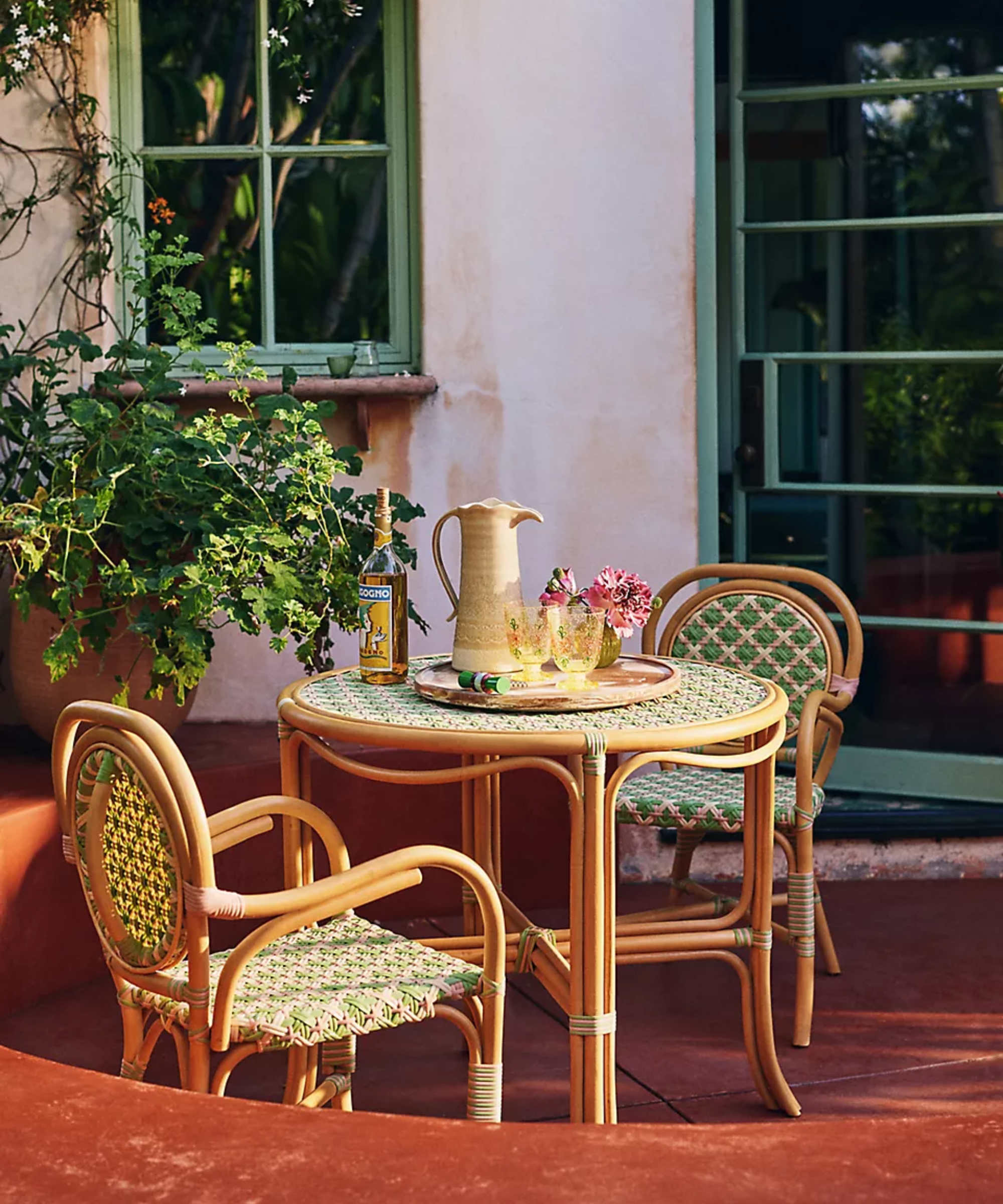 a bistro set on a terrace made from wood and woven with green and pink synthetic rattan weave
