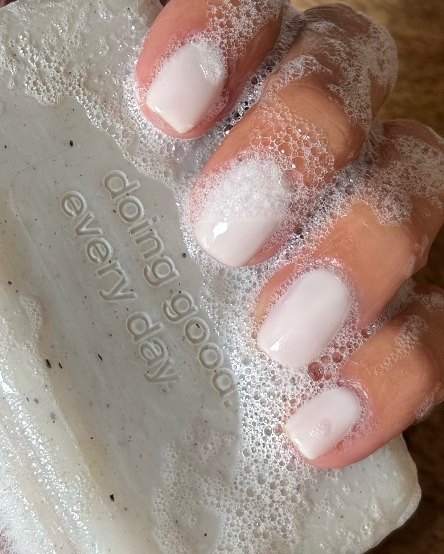 A woman holding a milky bar of soap with a milky manicure