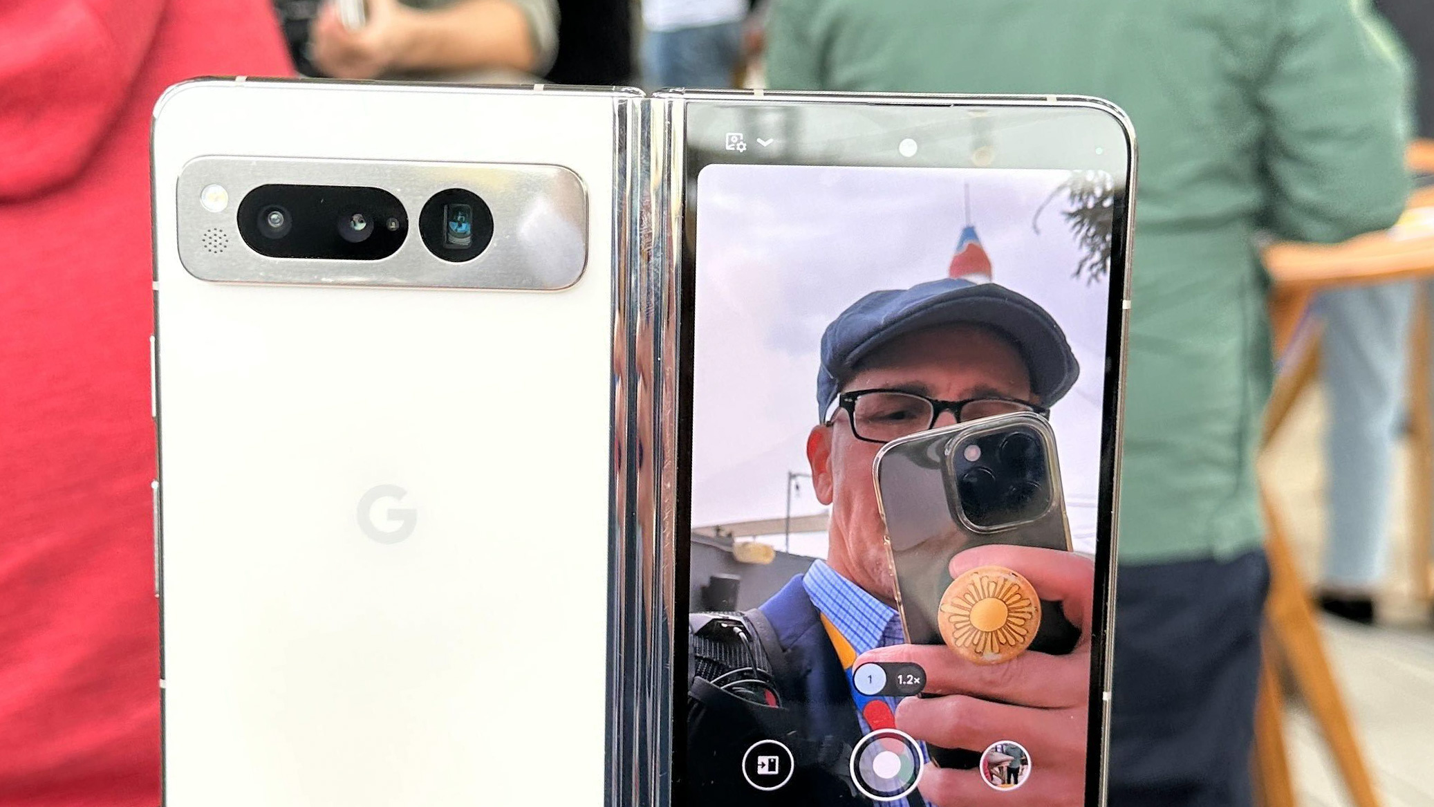 En mobiltelefon av typen Google Pixel Fold i hvitt med kameraet aktivert.