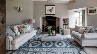 living room in farmhouse renovation project blue and white rug and open fire