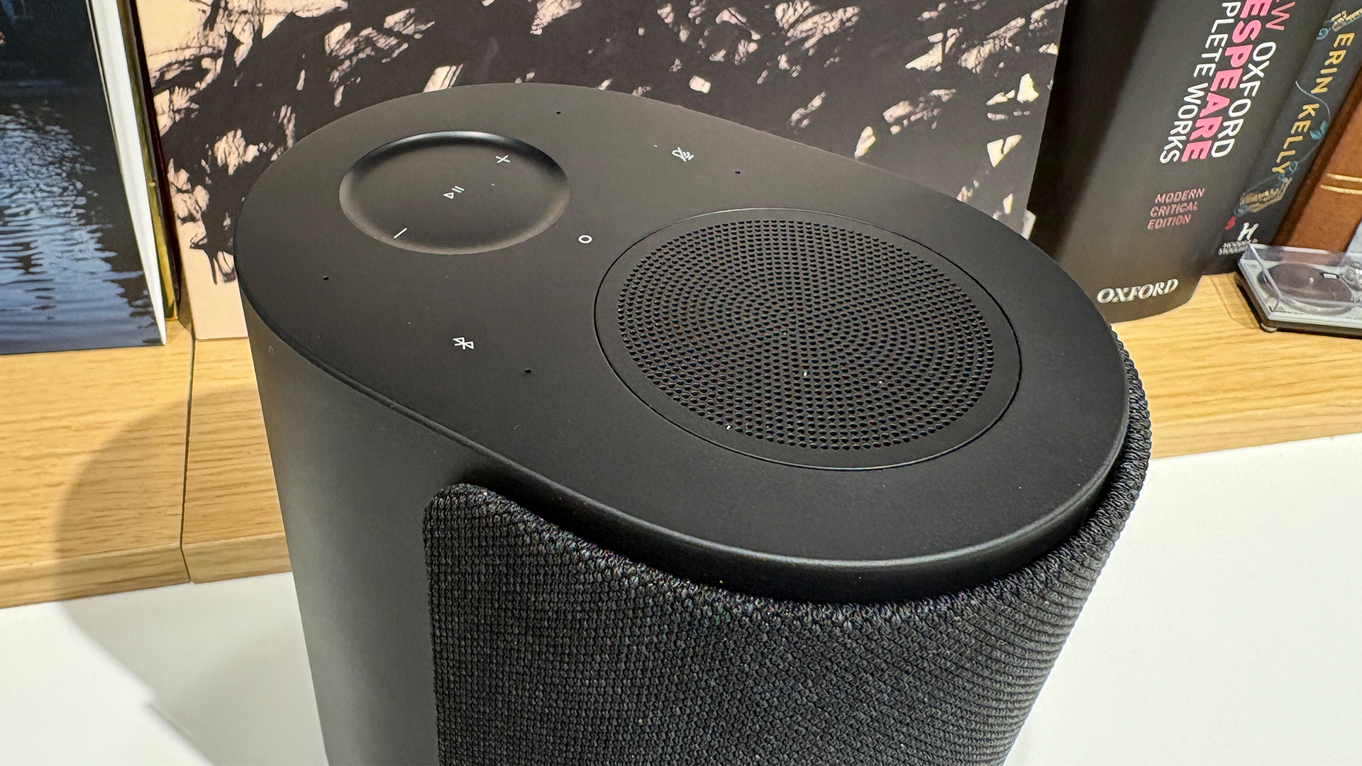 Bose Lifestyle Ultra Speaker wireless speaker in front of busy bookcase, top down review showing controls