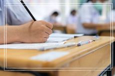 Students taking examinations at desk in classroom 