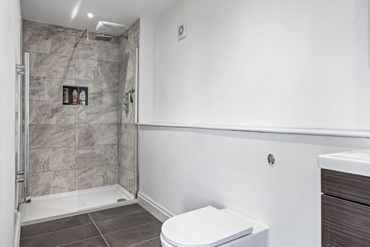 The bathroom includes a white toilet and grey tiles for the walk-in shower