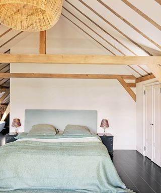 bedroom with vaulted ceiling, bed with aqua headboard and bedding and oversized woven pendant
