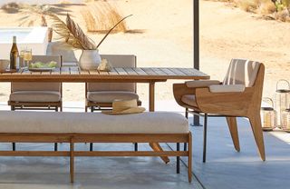 A sculptural teak outdoor dining set with sand dunes in the background