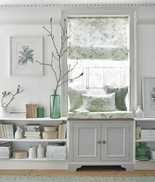 A white window seat with floral upholstery and built-in small living room storage ideas.