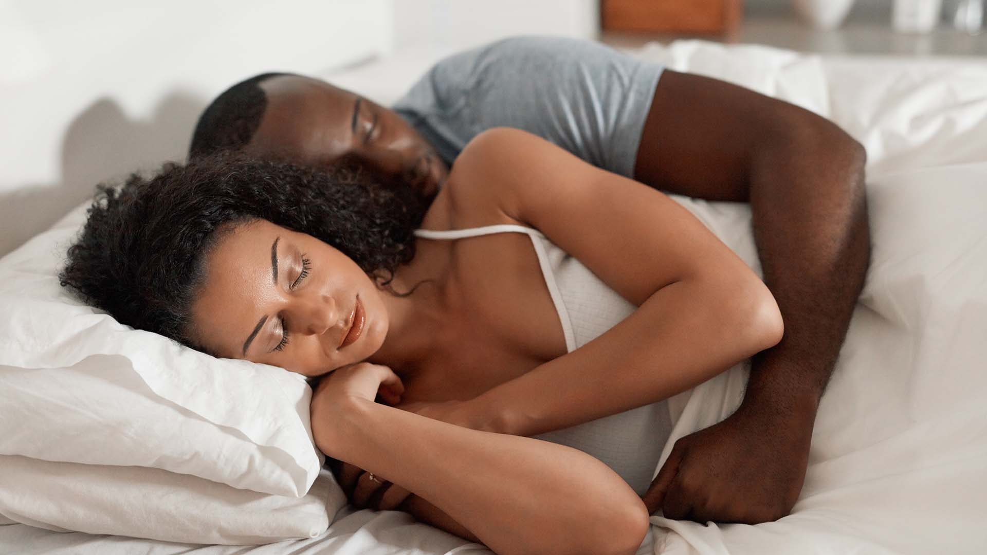 Two people lie next to each other in bed