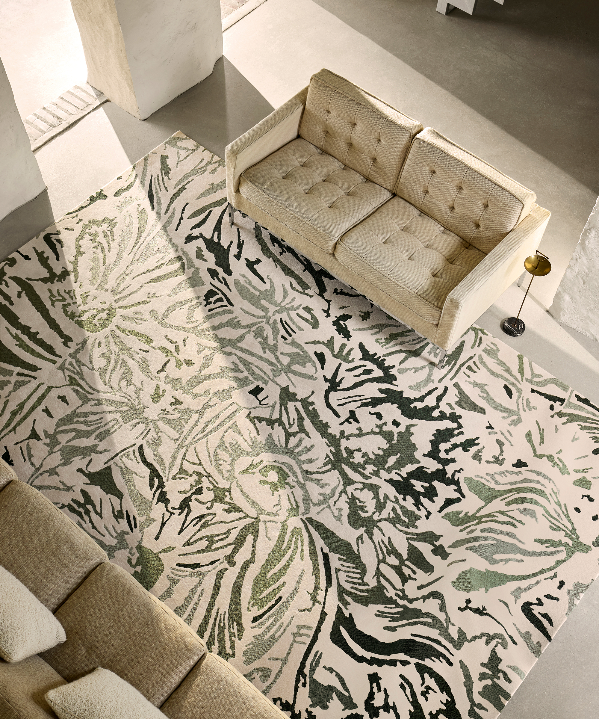 overhead shot of a graphic floral rug on the floor with a cream sofa on it
