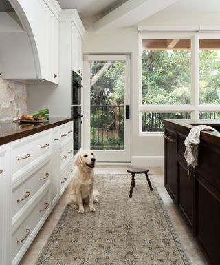 A white and wood kitchen with a earth toned runner on the floor