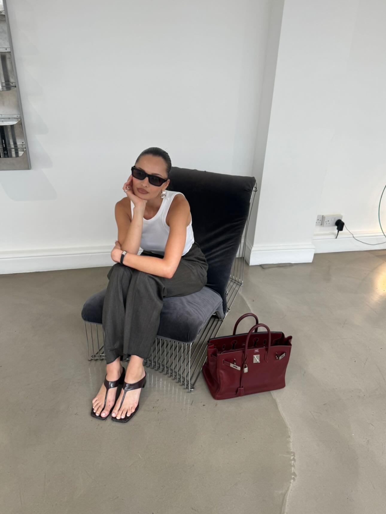 Pia Mance wearing a white tank top, gray pants, and stretch thong sandals.