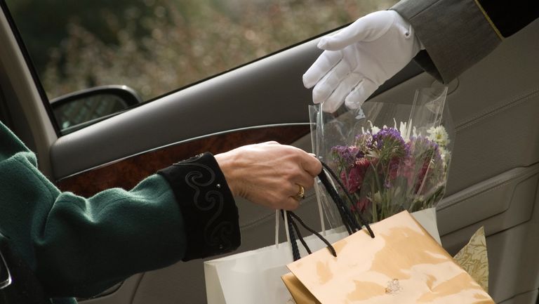 Woman passing shopping bags to valet - stock photo