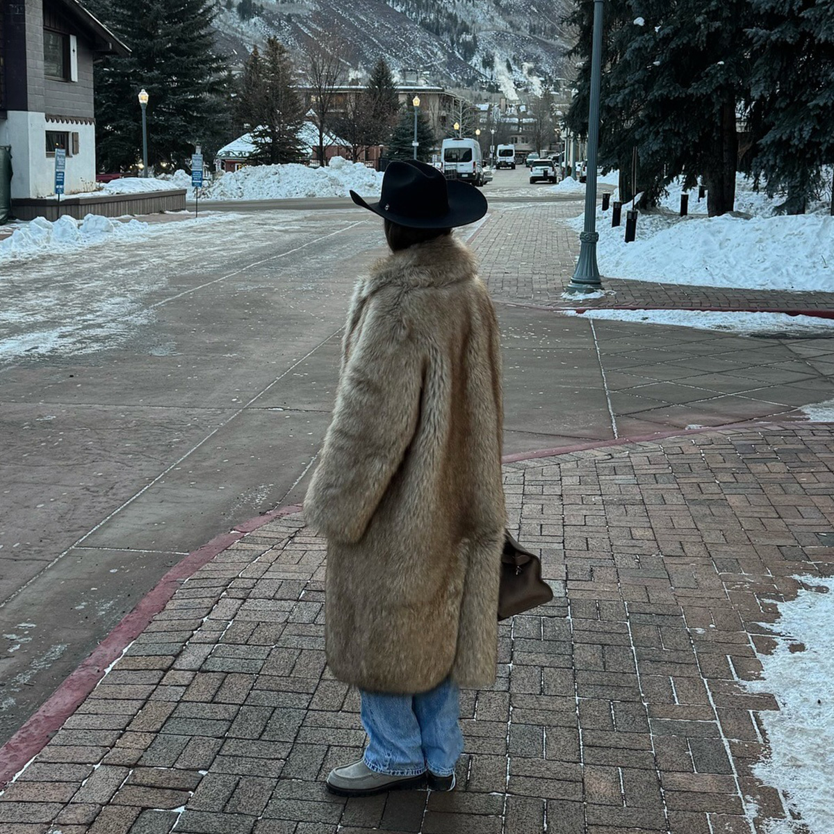 One woman wears a cowboy hat, fur coat, jeans, and loafers.