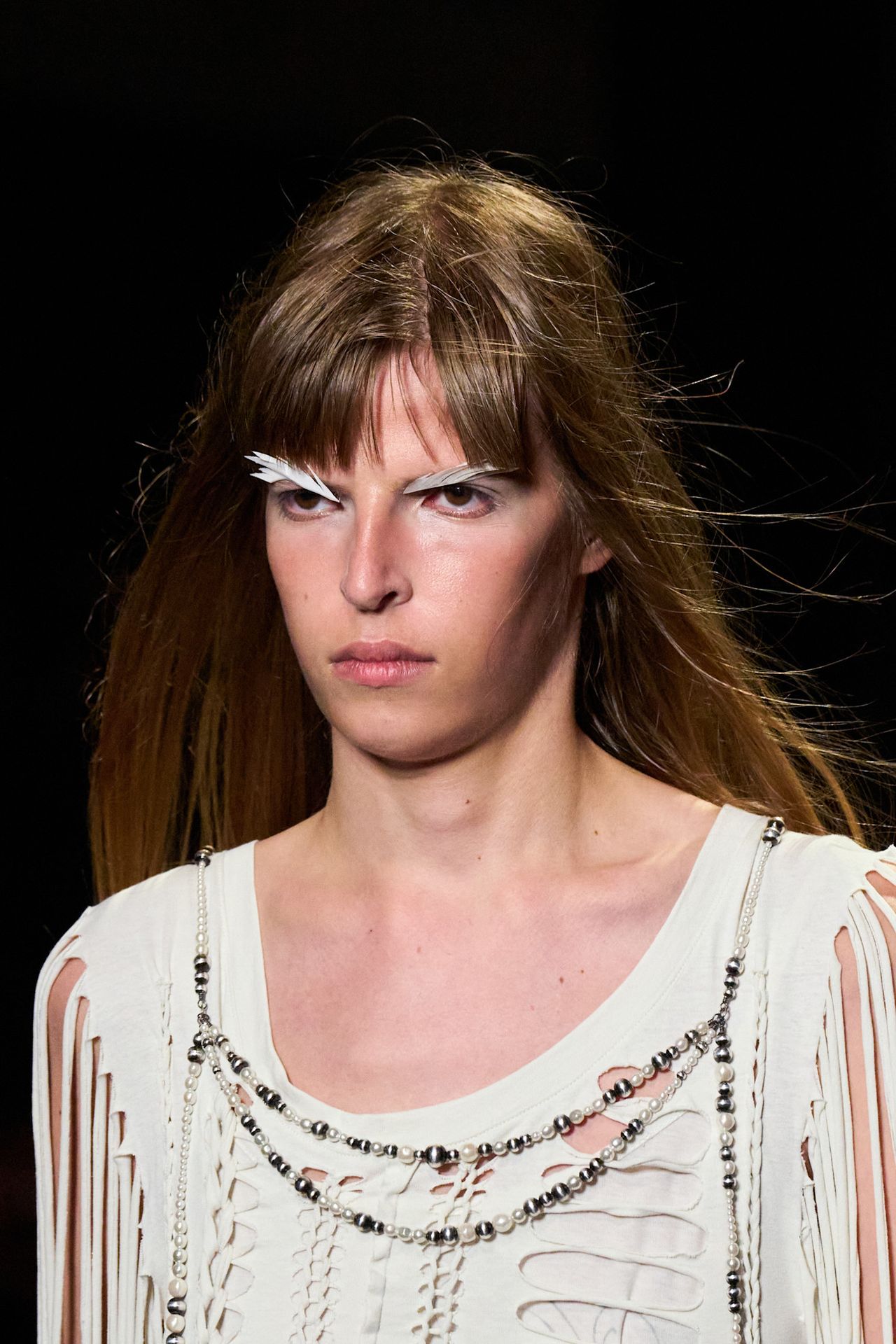Three women with feather accented eye makeup.