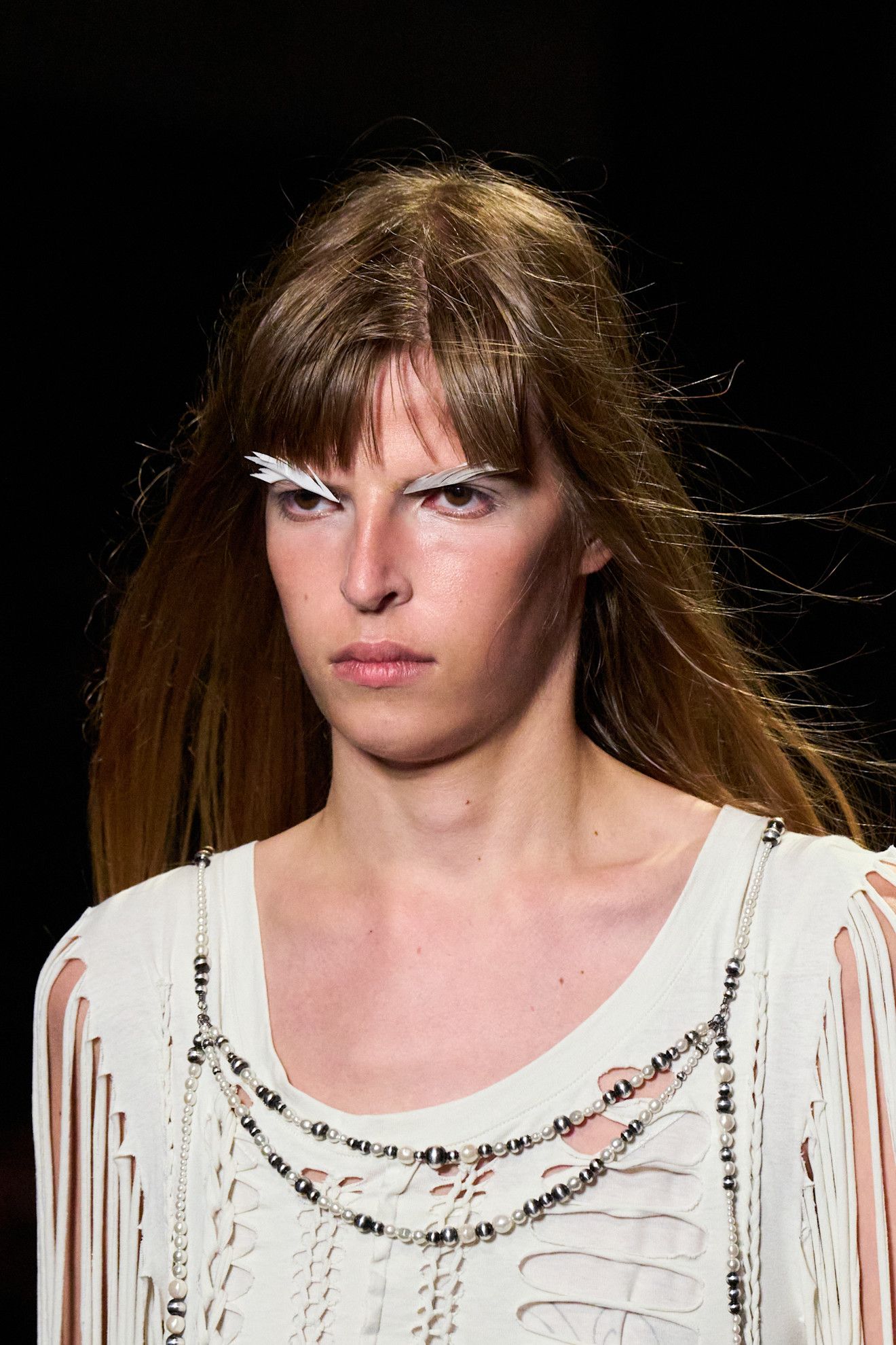 Three women with feather accented eye makeup.