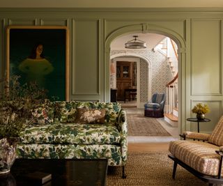 A green living room with an arched doorway and a patterned sofa