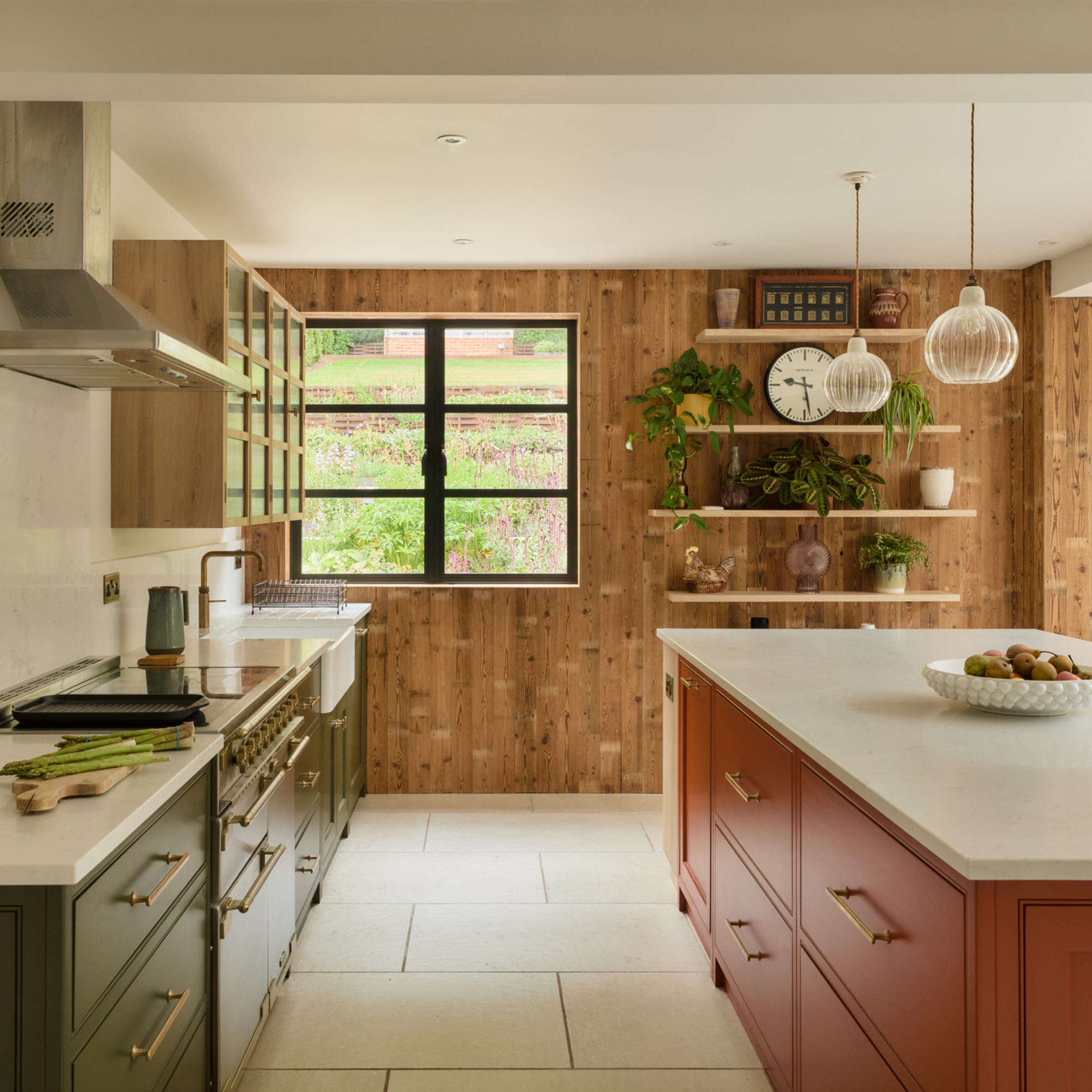 green and terracotta kitchen with cladded wall, open shelving, wall cabinet, fluted pendant lights, white work tops
