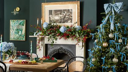 A dining room with a ribbon-decorated Christmas tree and a natural garland on the fireplace