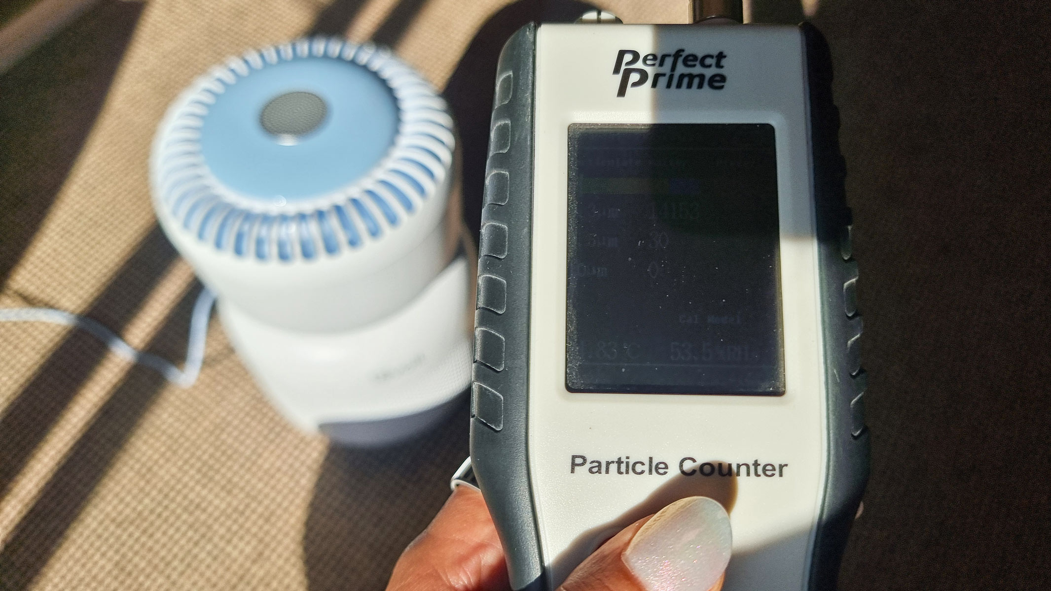 A close-up picture of our reviewer testing the Levoit Sprout air purifier with an air particle monitor