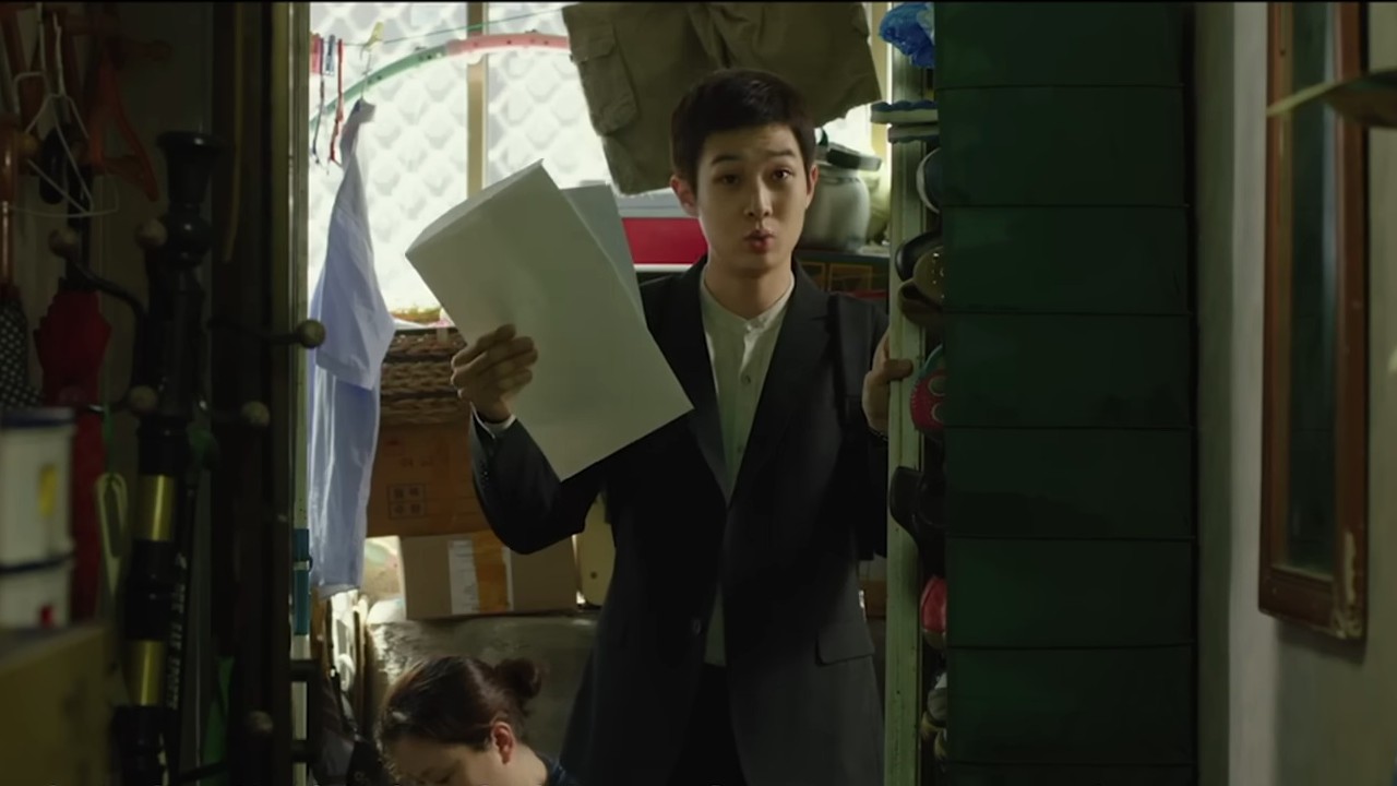 Choi Woo-shik holding up papers in Parasite