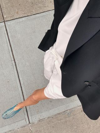 Courtney Grow in NYC wearing blue jelly flats by The Row with white shorts, a white tee, and a black blazer.