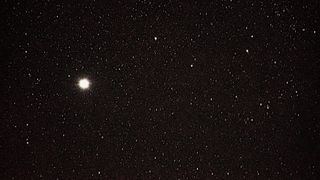 a vast array of stars in a black sky. on star, left of middle center is extra big and bright