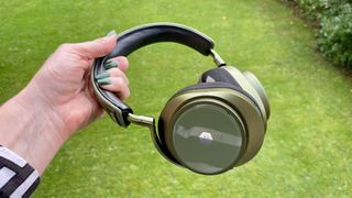 MW75 Neuro headphones held in a hand on green background