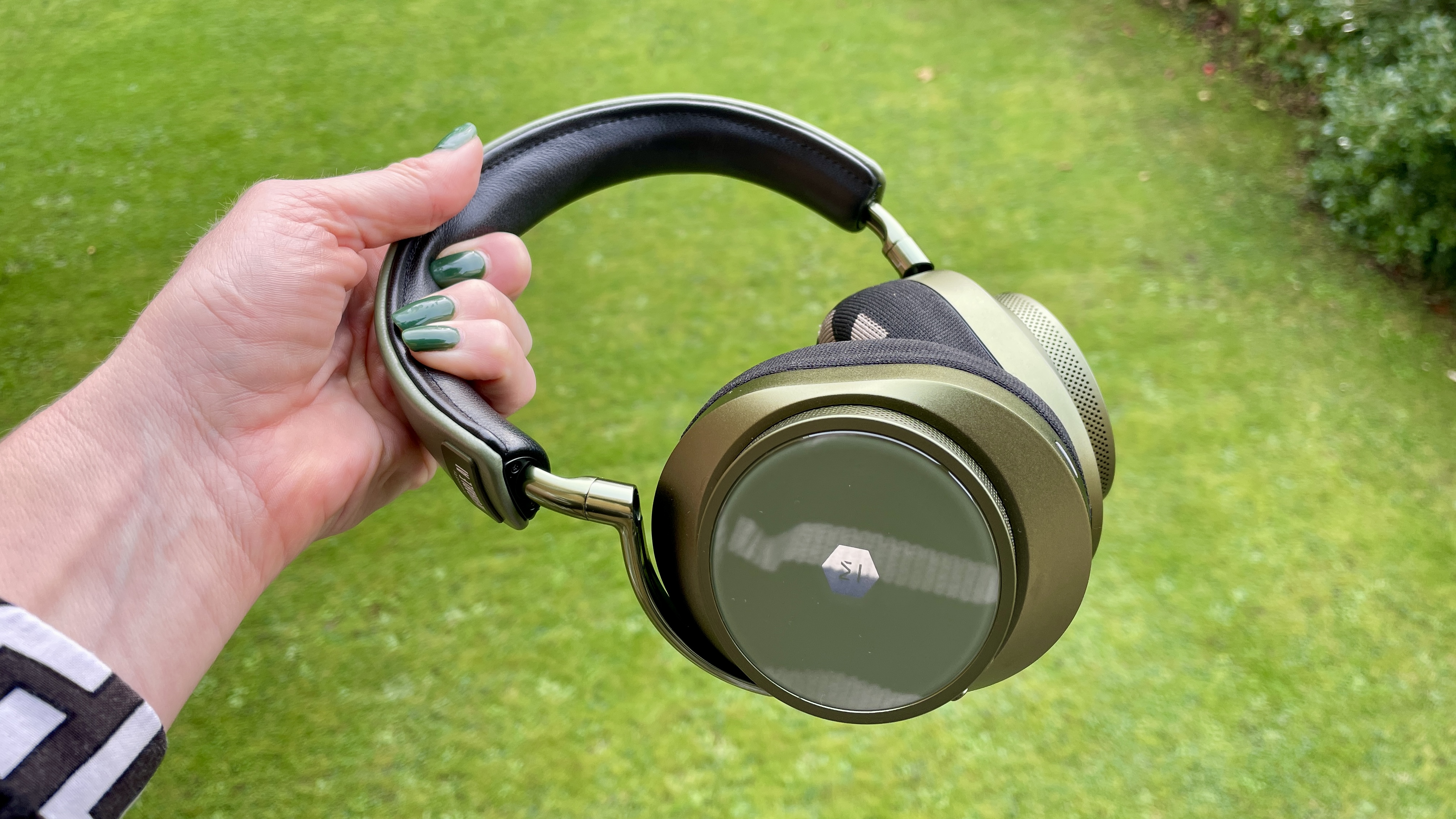 MW75 Neuro headphones held in a hand on green background