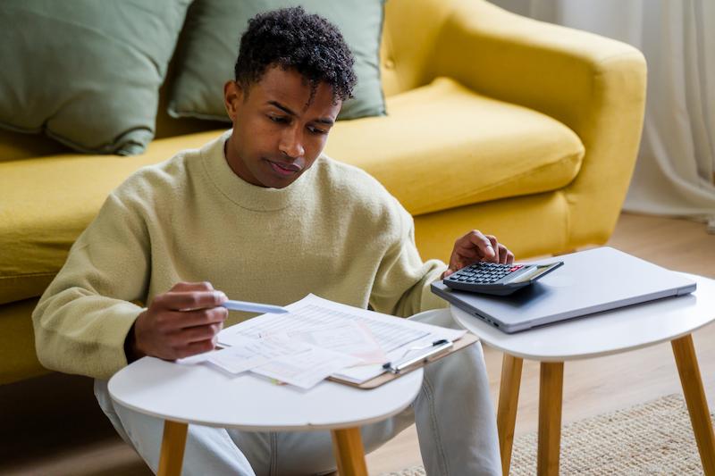 A student sat down working out finances with a piece of paper and a calculator