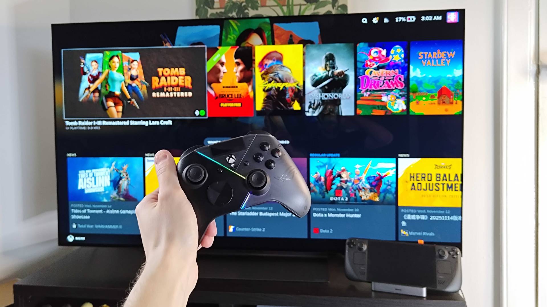 Hand holding controller infront of LG OLED TV with Steam Deck OLED conneted via Baseus docking station.