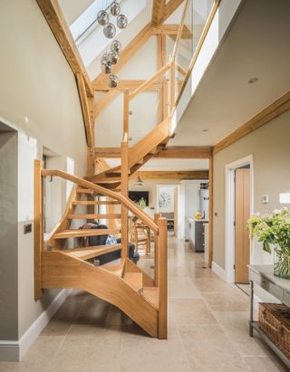 An oak staircase with a statement pendant light and glass balustrade