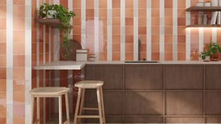 A kitchen with terracotta and white vertical stripe wall tiles, small square floor tiles, dark wood cabinetry and two wooden bar stools.