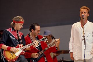 Mark Knopfler (left) and Jack Sonni of Dire Straits performing "Money for Nothing" with Sting (right) on stage during the Live Aid concert at Wembley Stadium in London, England on July 13, 1985