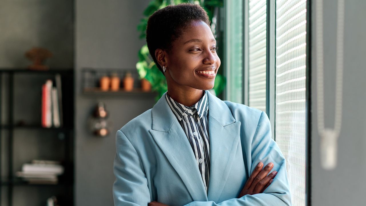 A financial planner smiles as she looks out the window of her office.