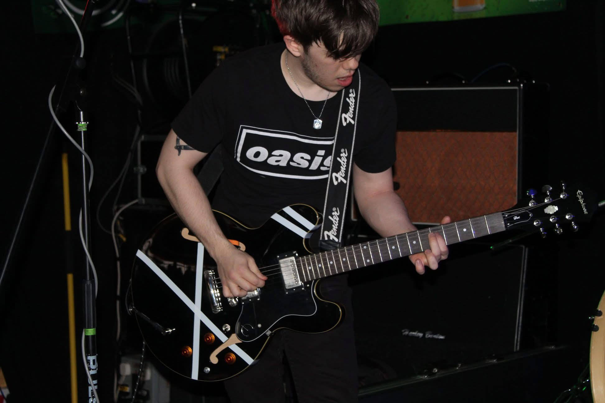 Matt Maidment on stage playing a black Epiphone Dot guitar with white tape placed on the guitar for decoration.
