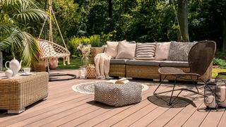 Rattan patio set and furniture on a wooden deck in a sunny garden