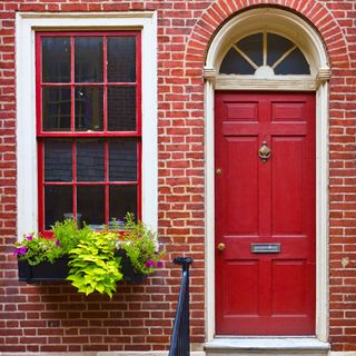 front door colour ideas, house exterior with red front door and matching woodwork, red painted window frames, steps up, window basket