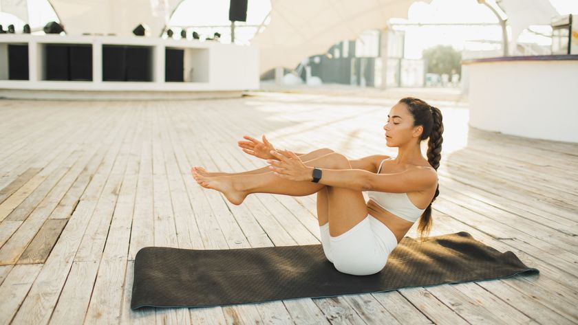 Woman outdoors on a yoga mat performing an ab exercise during ab workout