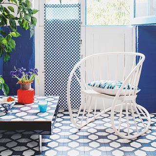 blue wall white door blue designed floor white chair and flower vase on table