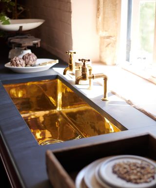 A polished brass sink with black countertop