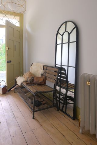 entryway with large floor standing black mirror and old fashioned bench with wire baskets