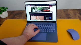 A masculine hand typing on a Microsoft Surface Laptop 13-inch