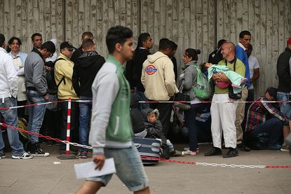 Refugees in Germany wait outside the Central Registration Office for Asylum Seekers