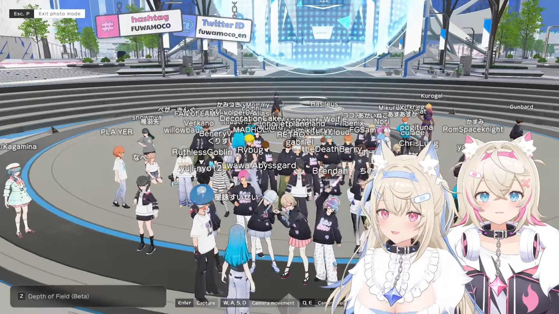 A screencap of a Hololive vtuber stream from Fuwamoco. The two vtubers have blonde hair and dog ears and are in the bottom right of the screen. Behind them is a scene in Holoearth, a virtual space for fans to hang out with vtubers as 3D avatars. A group of fans wearing black Fuwamoco hoodies are standing in a futuristic plaza with usernames floating above their heads.