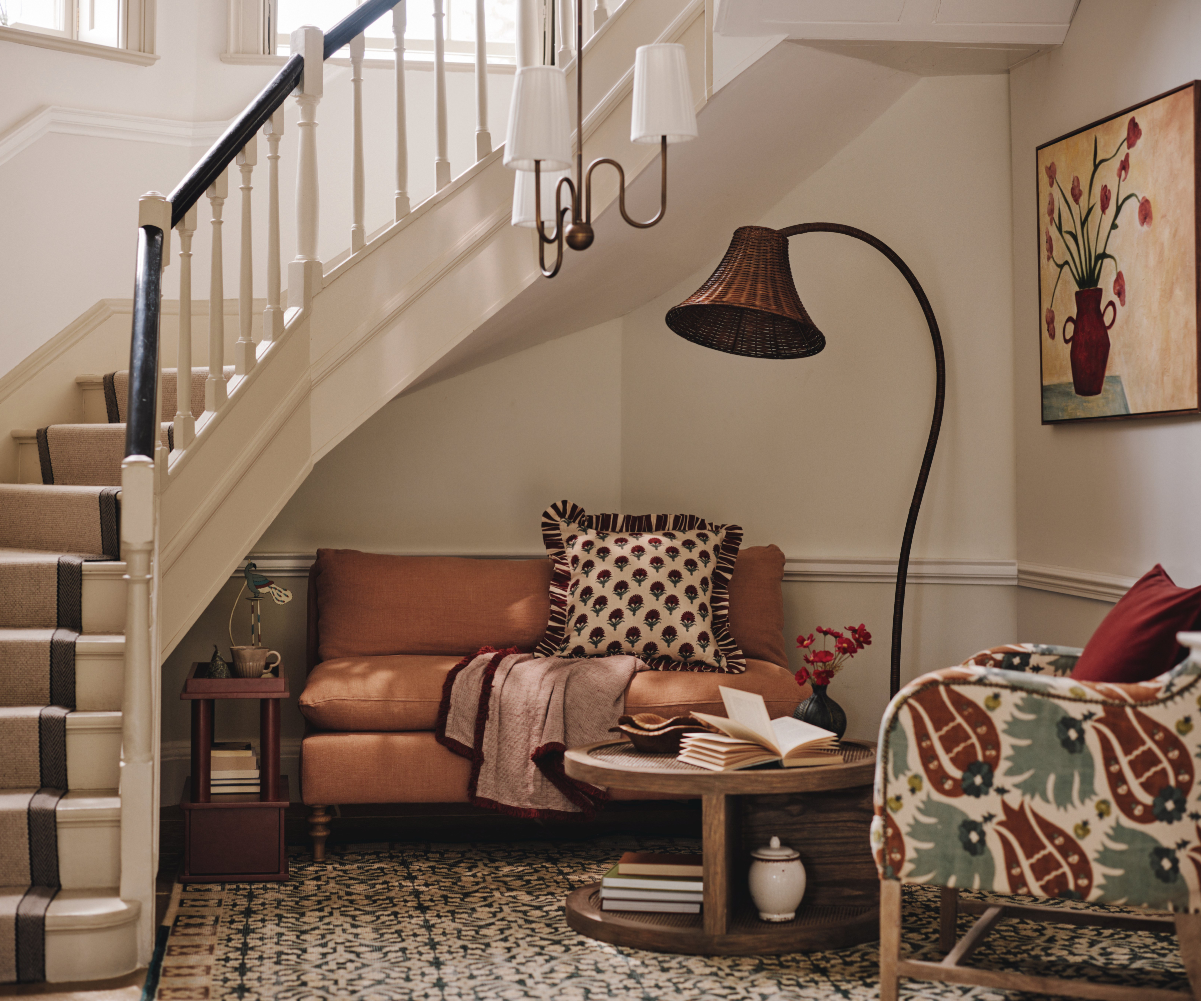 hallway with reading corner with small sofa, chair, pendant light and floor lamp with wicker shade