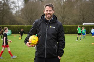 Jamie Redknapp holds a ball at a coaching session for children
