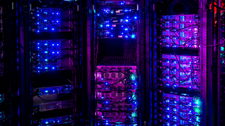 Illuminated servers in dark server room.