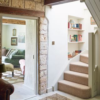 staircase in a cottage with exposed brick wall and shelves in a nook by the stairs