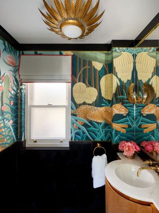Beautiful powder room with colorful, patterned wallpaper with a stunning design and golden fixtures