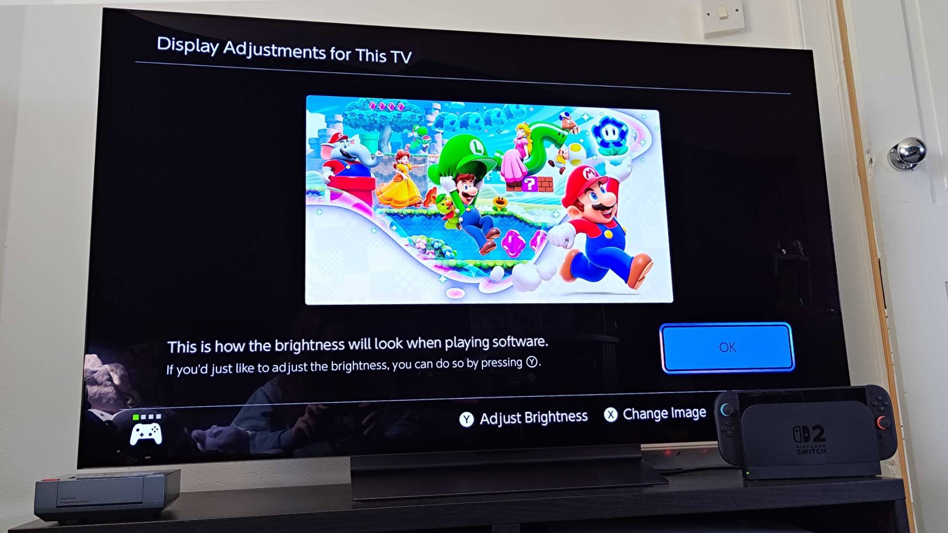 Switch 2 connected to LG OLED C4 on black TV bench with "Display Adjustments for This TV" screen open.