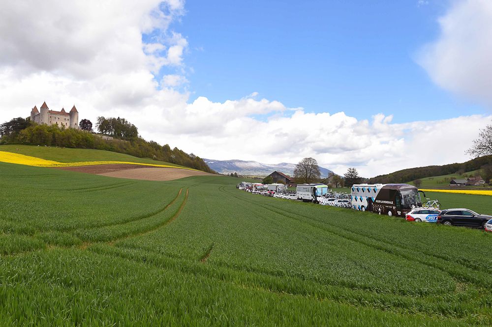 Castle Chateau Kastee overlooks a line if team vehicles at the 2016 Tour de Romandie